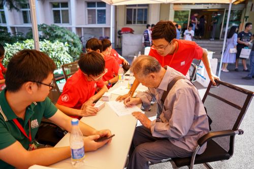 10月1日下午工学院签到处，一位退休教师在签到的同时，与学生志愿者交谈【学通社记者 李烨 摄】